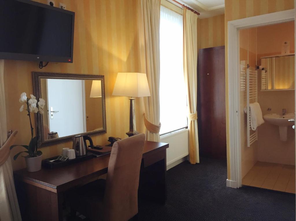 a hotel room with a desk and a mirror at Hotel Johannes Vermeer Delft in Delft