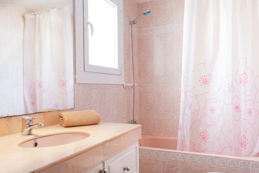 a bathroom with a sink and a shower curtain at Akira Flats Cadaqués Apartments in Cadaqués
