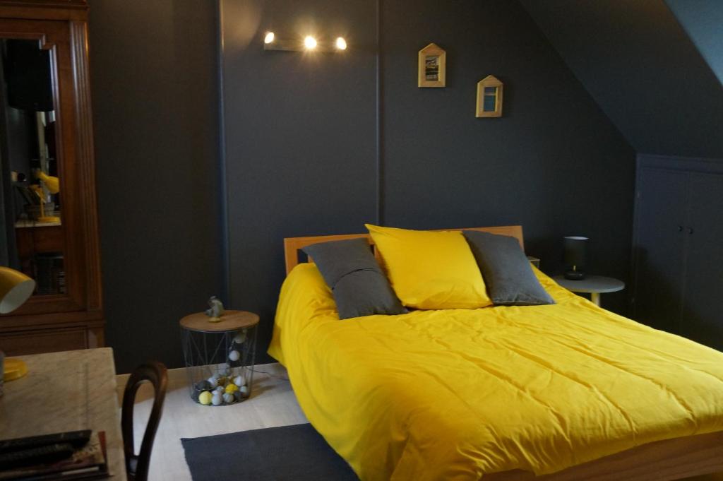 um quarto com uma cama amarela e duas mesas em Le Petit Chaton em Parigné-lʼÉvêque