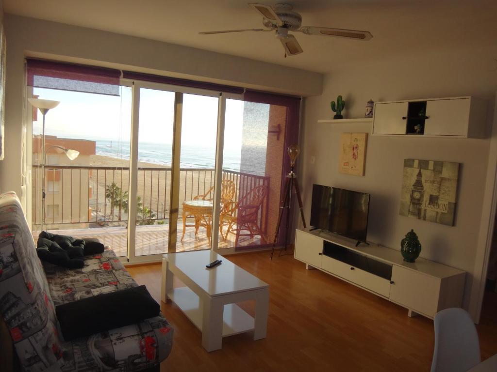 a living room with a couch and a television and a balcony at Torremar I in Torredembarra
