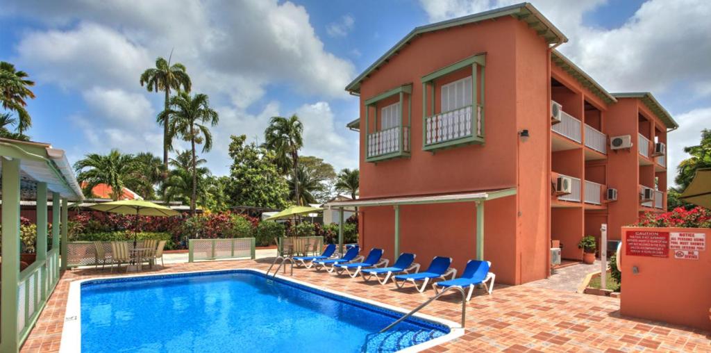 a villa with a swimming pool in front of a building at Worthing Court Apartment Hotel in Bridgetown