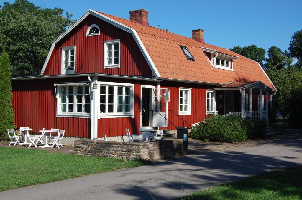 una casa roja con sillas y mesas delante. en Allégården Kastlösa Hotell, en Kastlösa