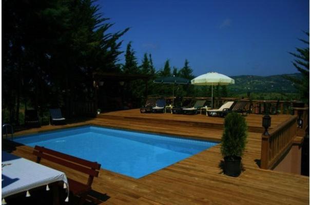 una piscina en una terraza de madera con sillas y sombrilla en Villa Pine Garden, en Agva