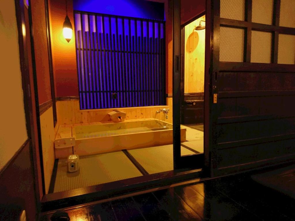 a bathroom with a bath tub and a mirror at Yadoya in Kyoto