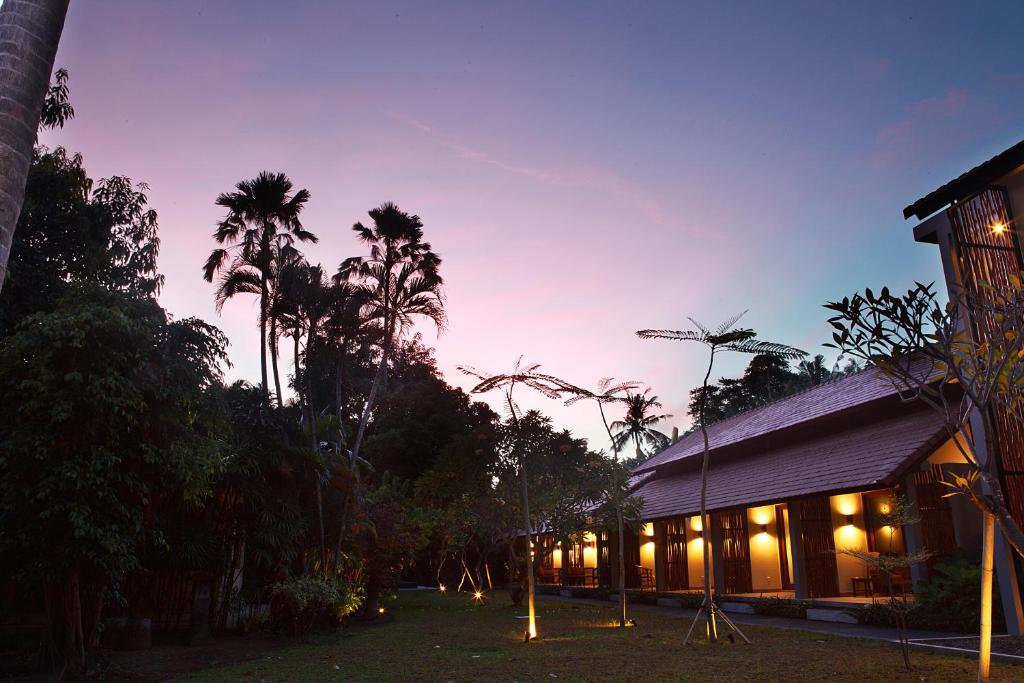 a building with lights and palm trees at night at Adys Inn in Legian