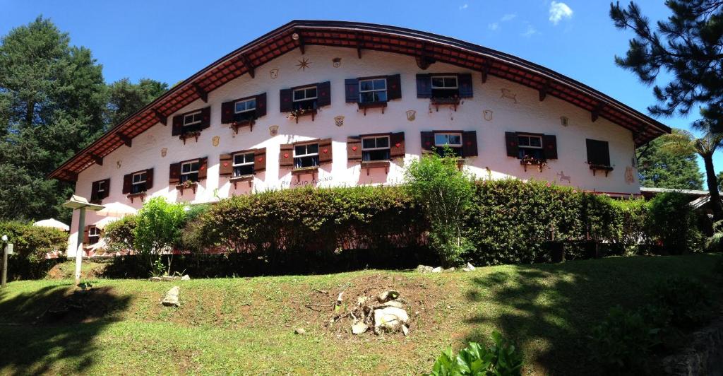 a large white building with windows and animals in front of it at Hotel Refúgio Alpino in Campos do Jordão