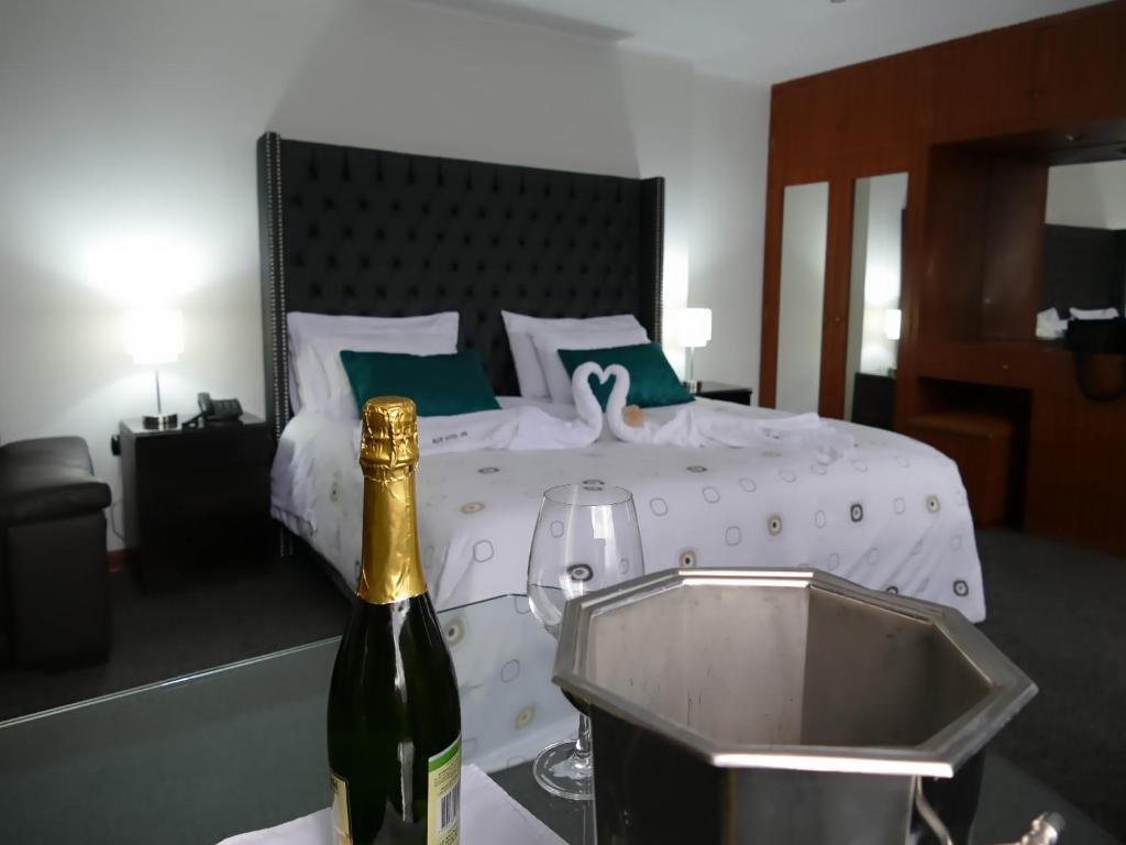 Una botella de vino en una mesa junto a la cama en Blub Hotel Spa, en Huancayo