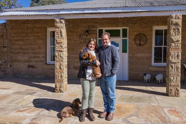 um homem e uma mulher em frente a uma casa com um cão em Hillmoor Stone Cottage em Hillvue