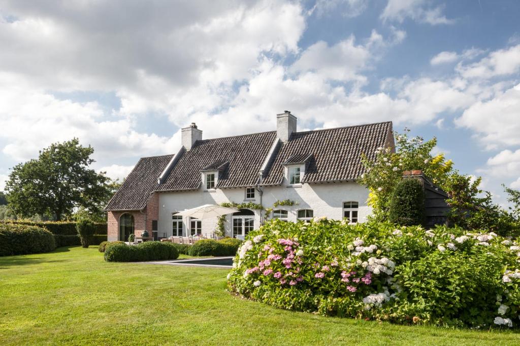 ein großes weißes Haus mit Blumen im Hof in der Unterkunft B&B De Lievde in Lievegem