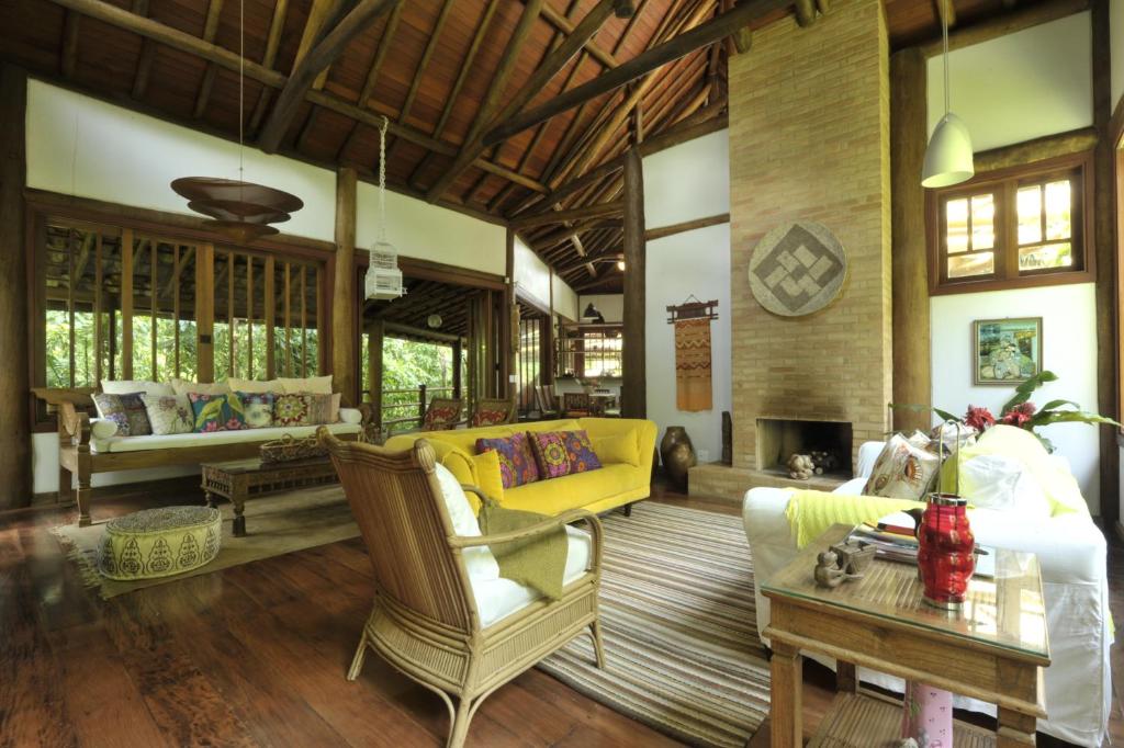 a living room with a yellow couch and a table at Casa Sertão de Camburi in Camburi