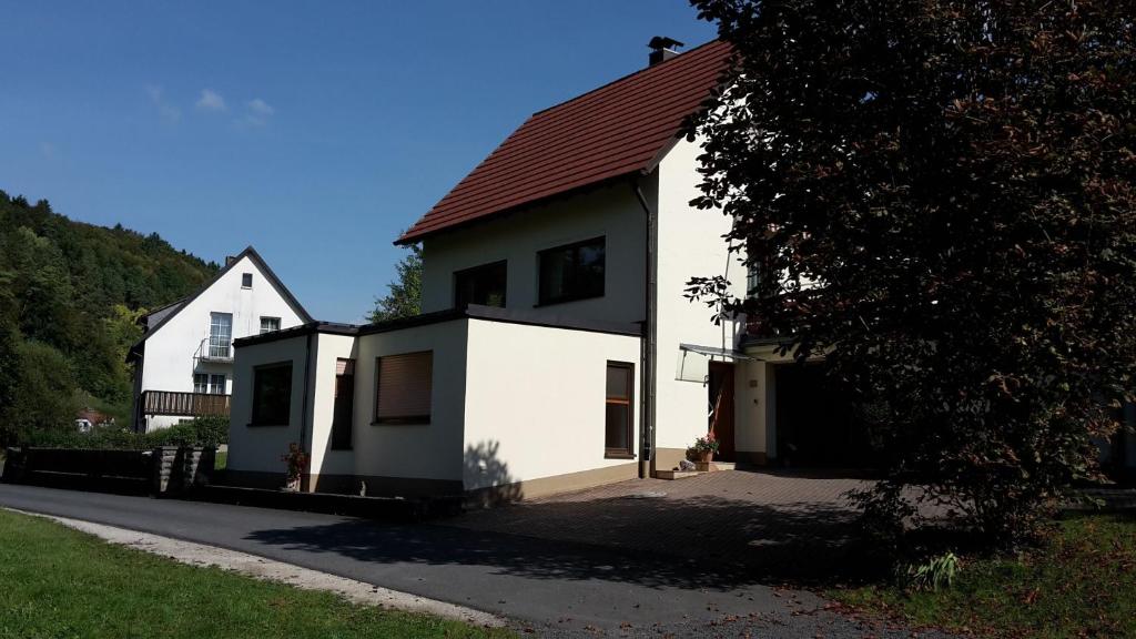 une maison blanche avec un toit rouge dans une rue dans l'établissement Ferienwohnung Lang, à Plankenfels