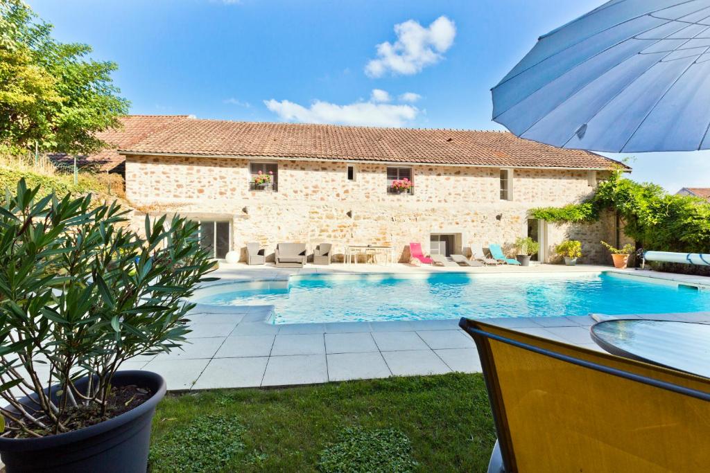 a villa with a swimming pool in front of a house at Clos De La Gourmandière in Saint-Lothain