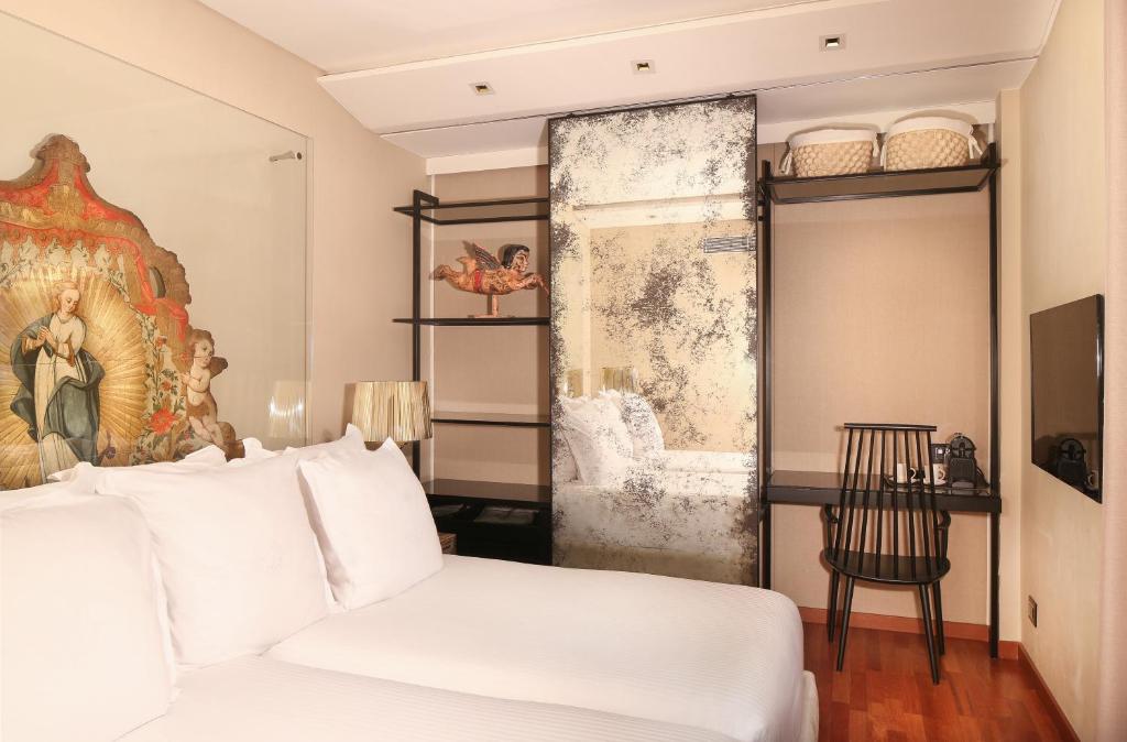 a bedroom with a white bed and a chair at Claris Hotel & Spa GL, a Small Luxury Hotel of the World in Barcelona