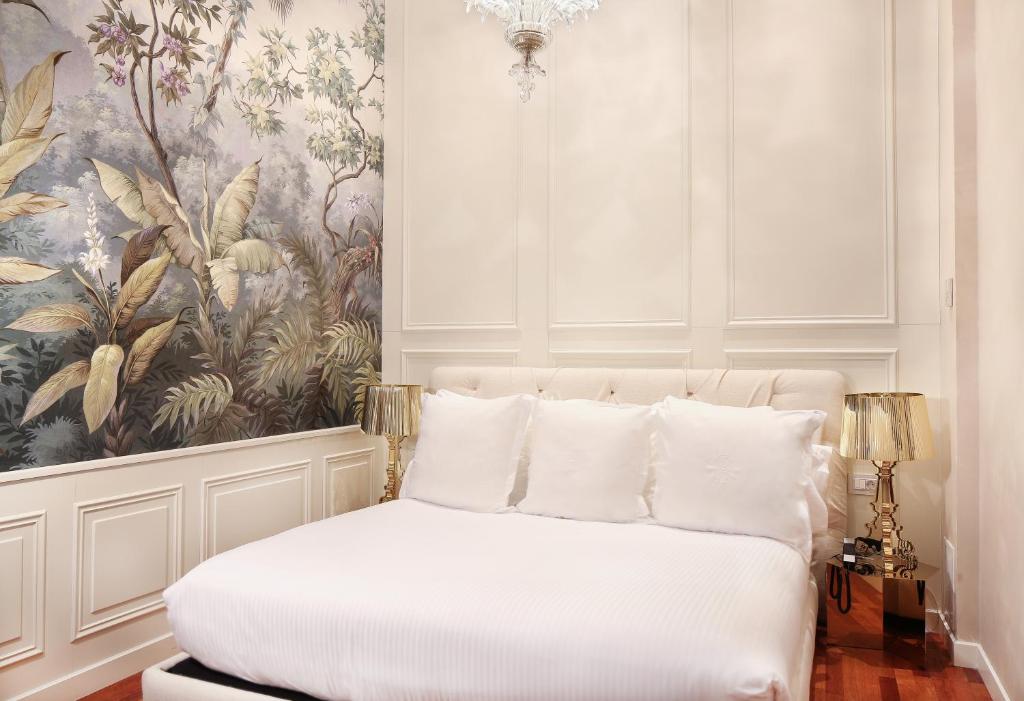 a bedroom with a white bed with a painting on the wall at Claris Hotel & Spa GL, a Small Luxury Hotel of the World in Barcelona