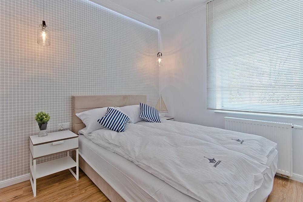 biała sypialnia z łóżkiem i stolikiem nocnym w obiekcie Imperial Apartments - Balticana w mieście Sopot