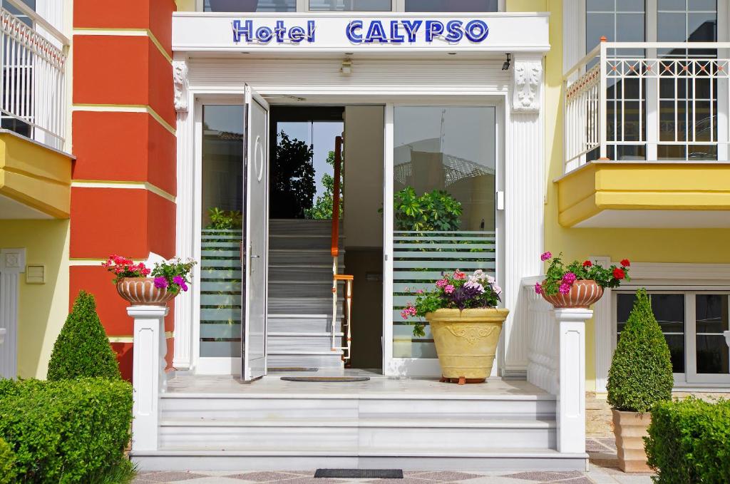 a hotel lobby with stairs and flowers in pots at Calypso Beach Hotel in Paralia Katerinis