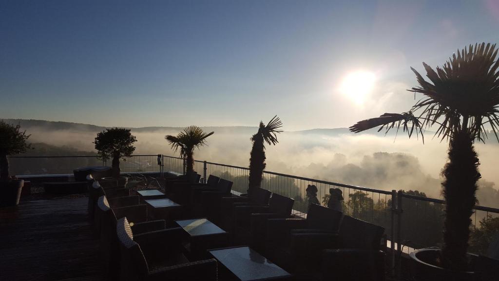 a row of chairs on a balcony with the sun in the background at Vitalhotel König am Park in Bad Mergentheim