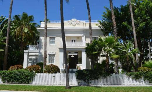 une maison blanche avec des palmiers devant elle dans l'établissement Weatherstation Inn Circa 1911, à Key West