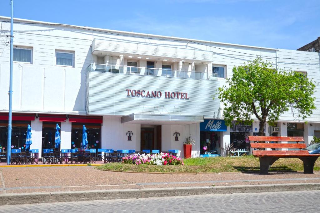 a building with a wooden bench in front of it at Toscano Hotel in Rafaela