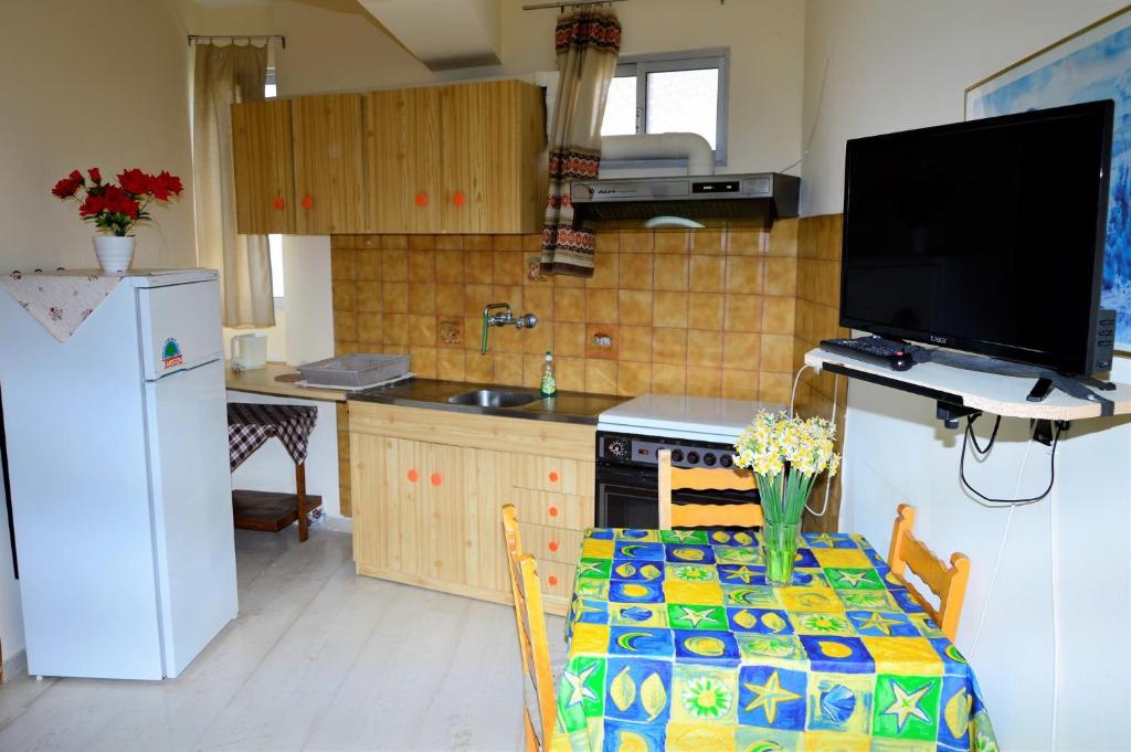 een keuken met een tafel, een televisie en een koelkast bij Pantelis in Póros