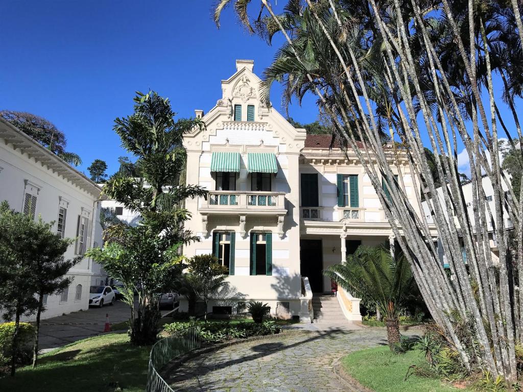 a large white house with a clock on the front of it at Hotel Casablanca Imperial in Petrópolis