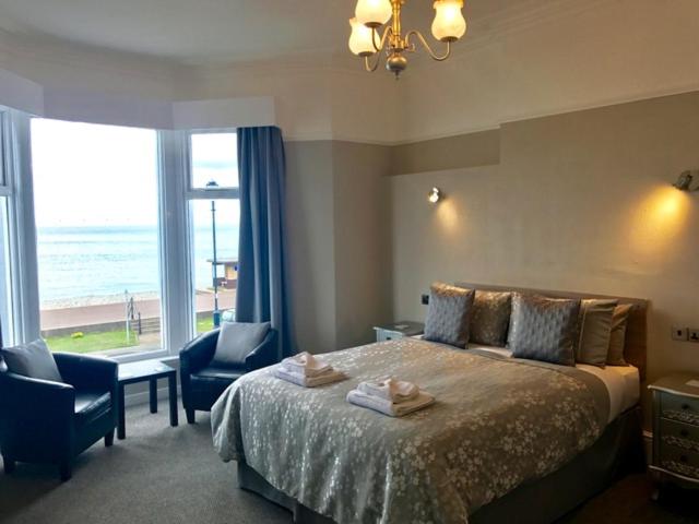 a bedroom with a bed and a view of the ocean at Bromwell Court in Llandudno