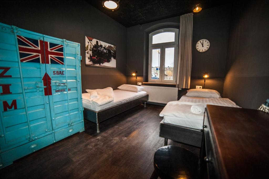 Pokój z dwoma łóżkami i zegarem na ścianie w obiekcie Hostel am Bahnhof w mieście Suhl