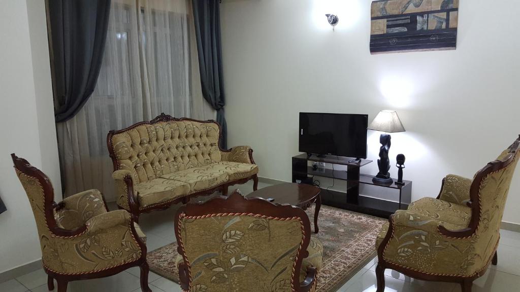 a living room with a couch and chairs and a tv at Résidence La Roseline in Yaoundé