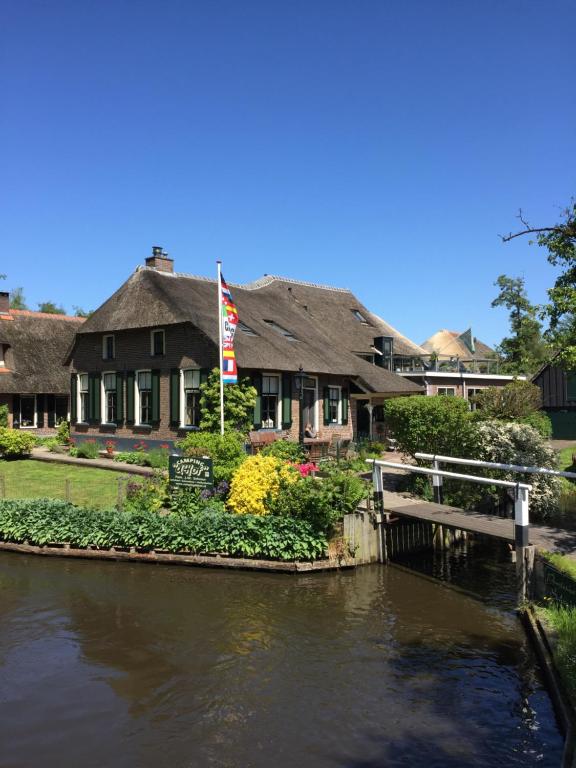 a house next to a river with a bridge at Bed & Bike De Hofstee in Giethoorn