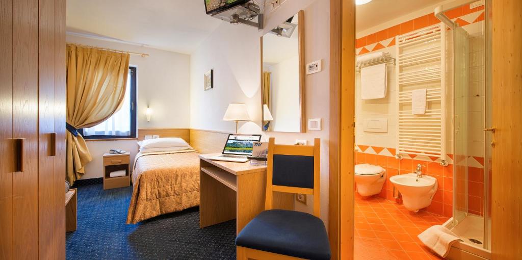 Cette chambre comprend un lit et un bureau avec un ordinateur portable. dans l'établissement Hotel Cristallo, à Peio Fonti