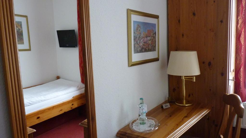 a mirror in a room with a bed and a lamp at Gasthof Willenbrink in Lippetal