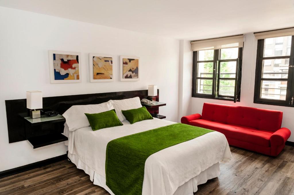 Hotel Bogota Virrey في بوغوتا: غرفة نوم بسرير كبير واريكة حمراء