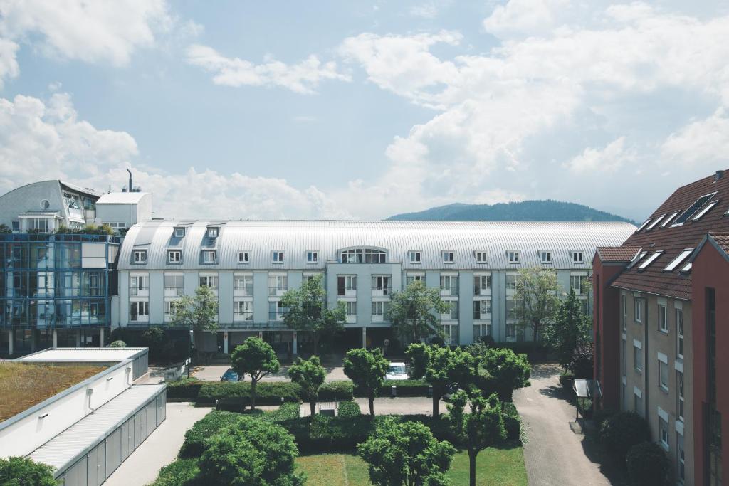 ein großes weißes Gebäude mit Bäumen im Innenhof in der Unterkunft StayInn Hostel und Gästehaus in Freiburg im Breisgau