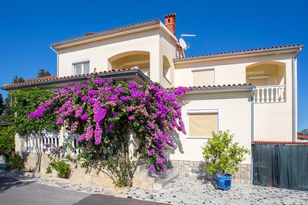 Una casa con flores púrpuras a un lado. en Guest House Croatia, en Fažana