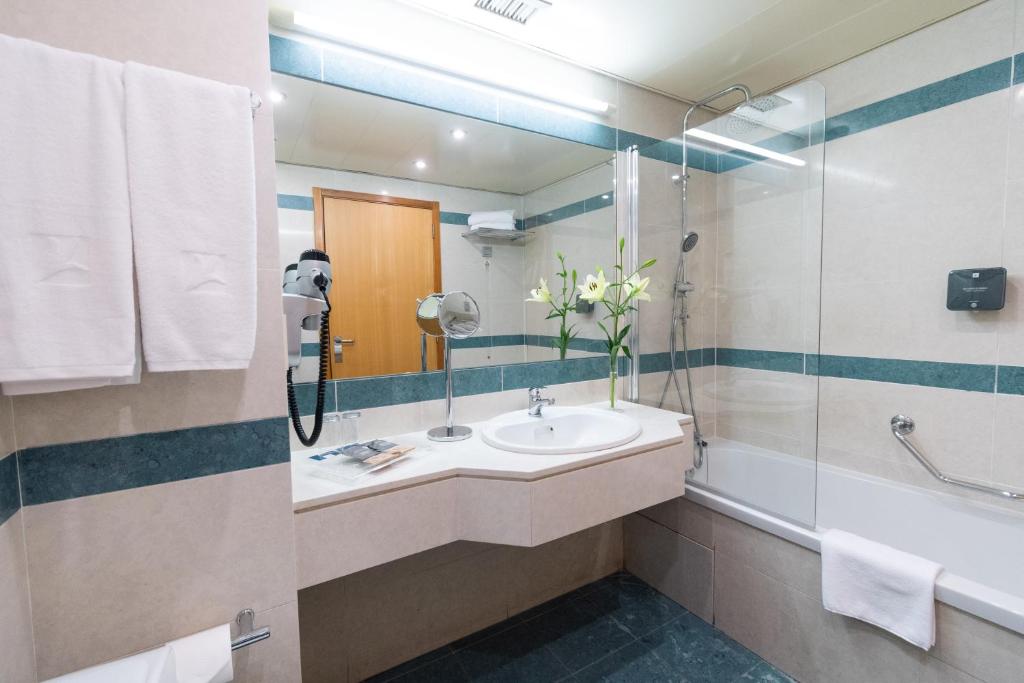A bright bathroom combines a corner vanity with a glass-screened bathtub.