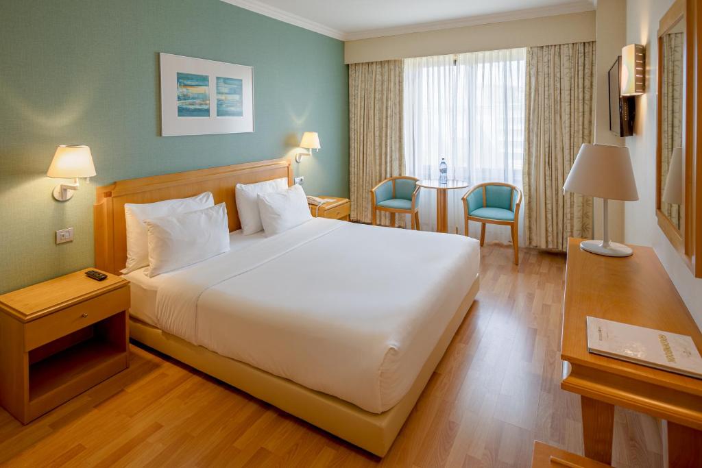 A bright double bedroom with a window-side sitting area and built-in work surface.