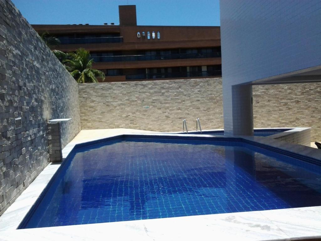 a swimming pool in a building with a brick wall at Terrazzas Flat in João Pessoa