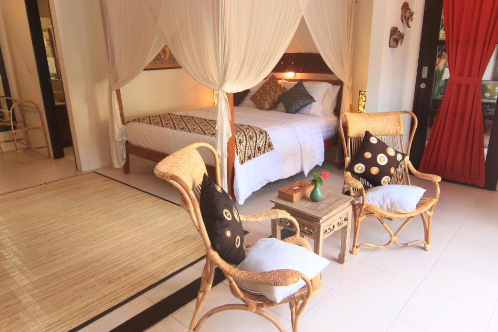 a bedroom with a bed and two chairs and a table at Kembali Lagi Guest House in Sanur
