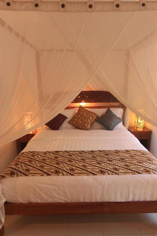 a bedroom with a bed with a mosquito net at Kembali Lagi Guest House in Sanur