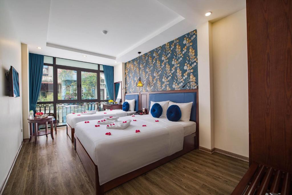a bedroom with two beds with red flowers on them at Holiday Emerald Hotel in Hanoi