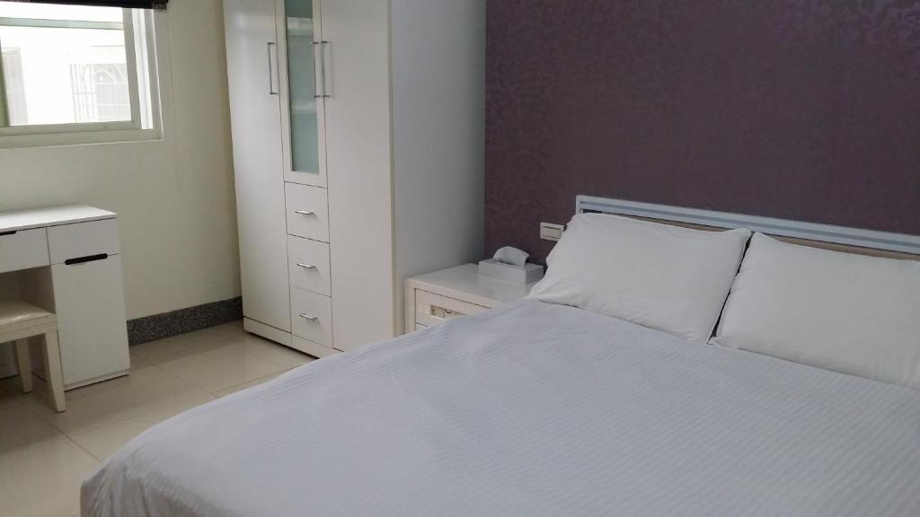 金寧鄉的住宿－愛玩客107，卧室配有白色的床和窗户。