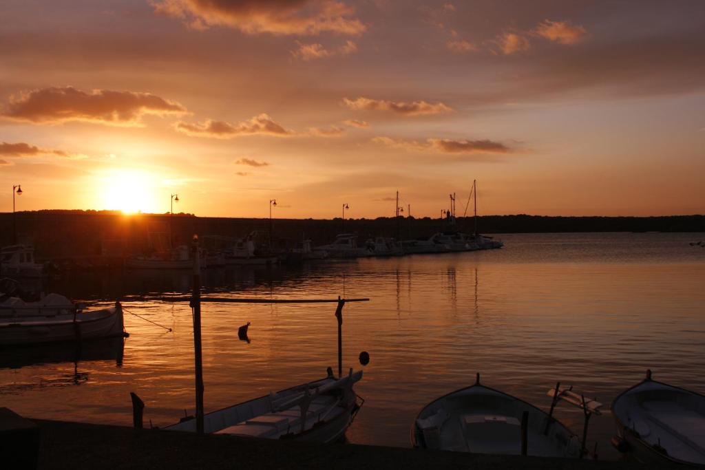 a sunset over a harbor with boats in the water at Hostal S'Algaret in Fornells