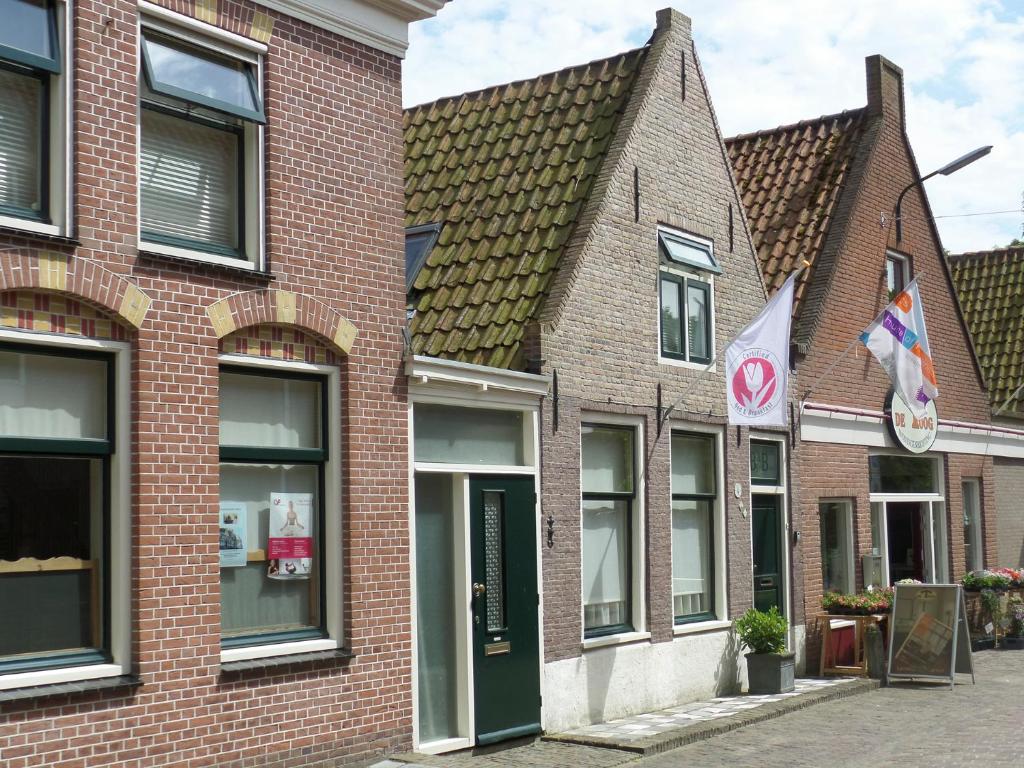 ein rotes Backsteingebäude mit Fenstern und einer Flagge in der Unterkunft Bij de Buren in Enkhuizen