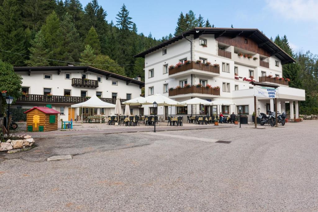 a large white building with tables and umbrellas at Hotel Paradiso in Sarnonico