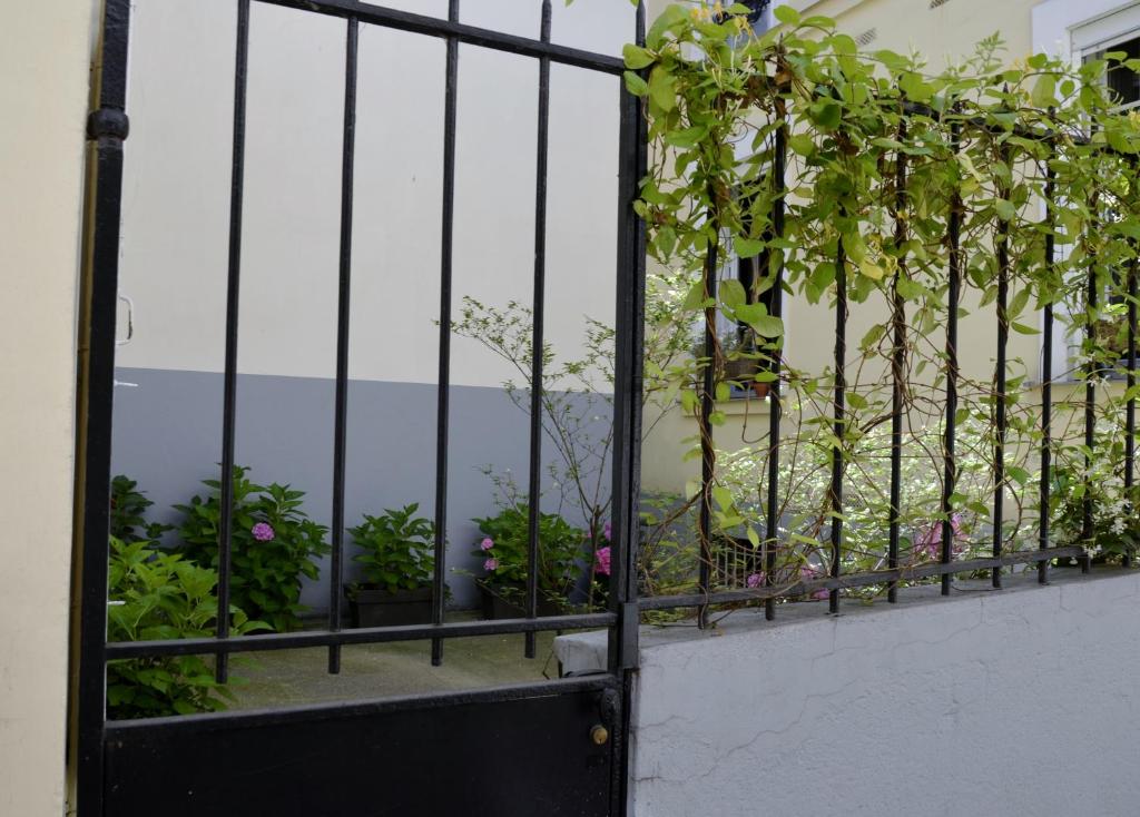 ein schwarzes Tor mit Blumen auf dem Balkon in der Unterkunft La Cour du 5ème - Chambre d'hôtes in Paris