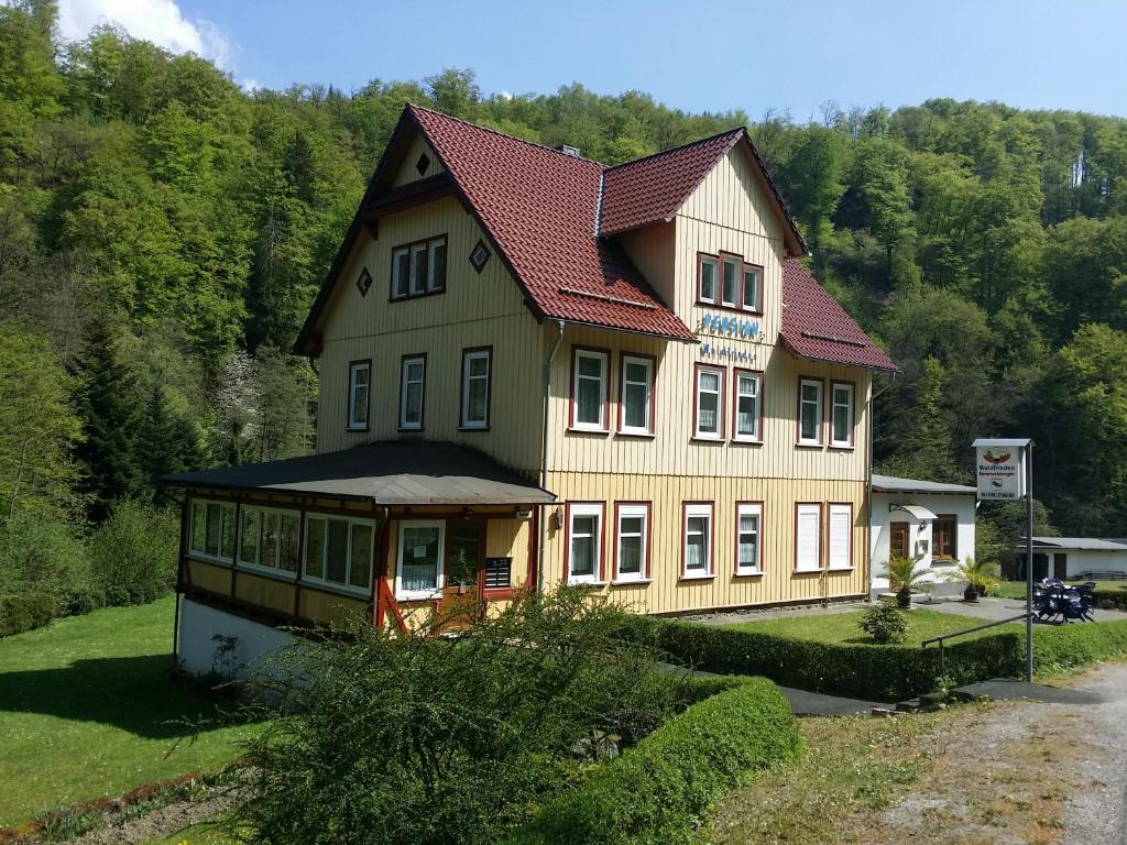 une grande maison jaune avec un toit rouge dans l'établissement Pension Waldfrieden, à Thale