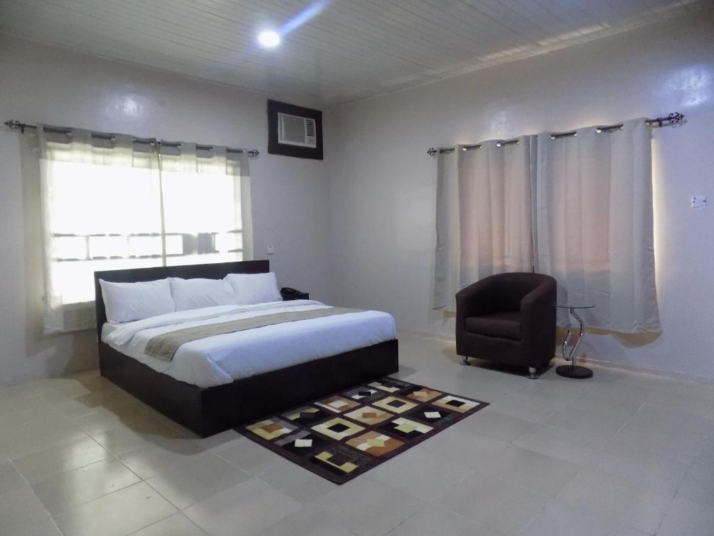 a bedroom with a bed and a chair at Posh Hotel and Suites Ikeja in Ikeja