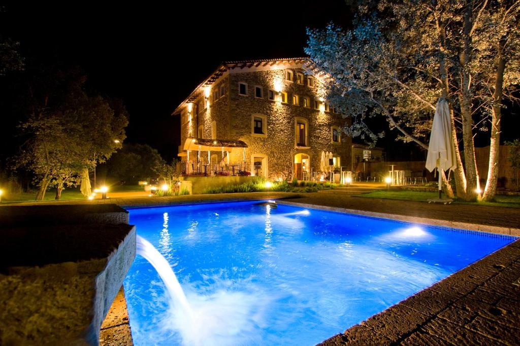 a swimming pool in front of a house at night at Molí Blanc Hotel in Jorba