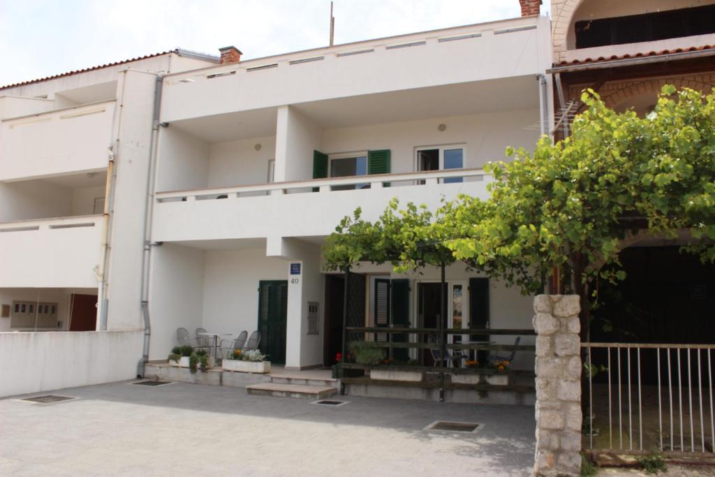 Una casa blanca con un árbol delante. en Apartments Mostak, en Baška