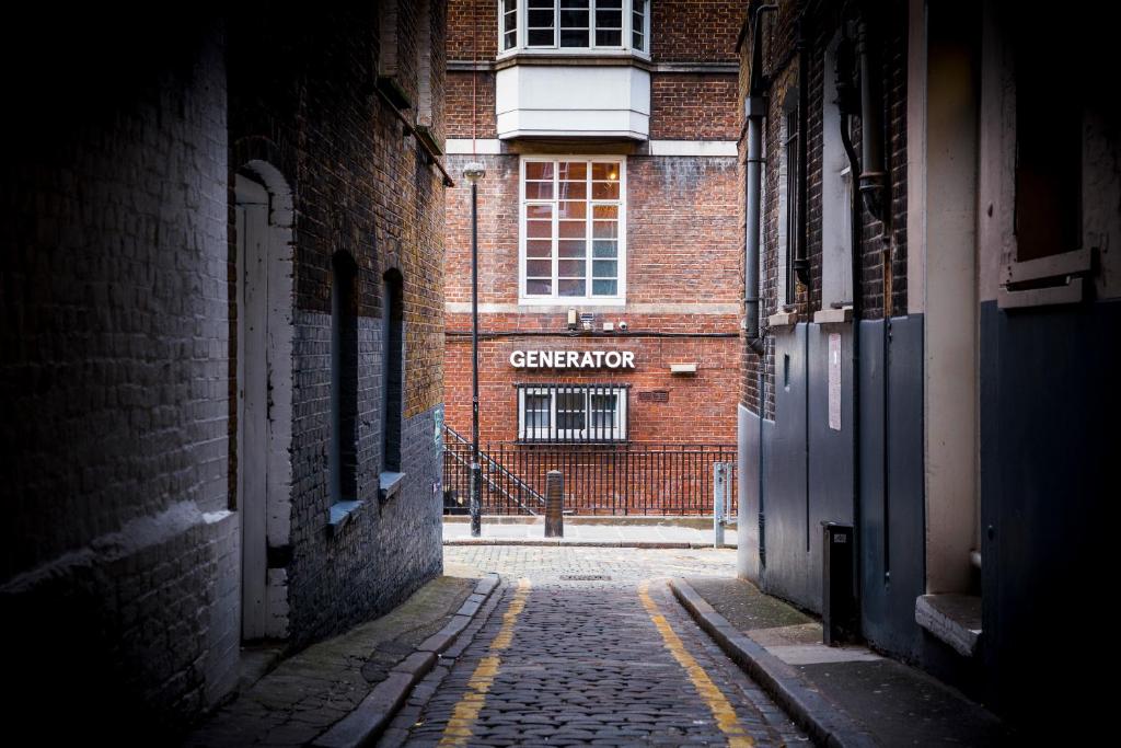 an alley with a brick building with a sign on it at Generator London in London